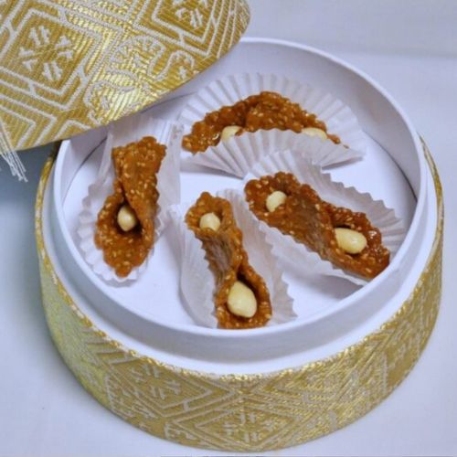 Gâteaux marocains Blira au sésame et à la fleur d’oranger, joliment présentés dans des caissettes blanches à l’intérieur d’une boîte décorée de motifs dorés.